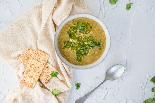 Kom romige witte aspergesoep met verse kruiden en stukjes asperge op houten tafel